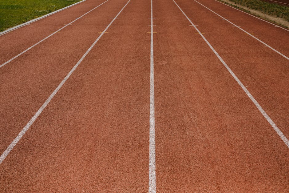 An empty running track with clearly marked white lanes on a sunny day, ready for sports activities