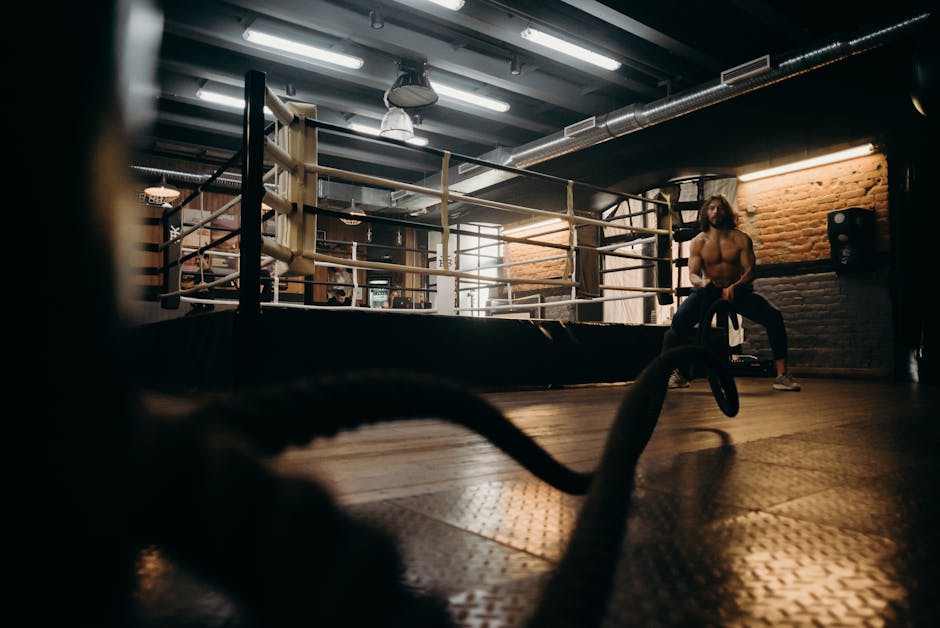 Muscular man engaged in intense rope workout inside industrial gym setting