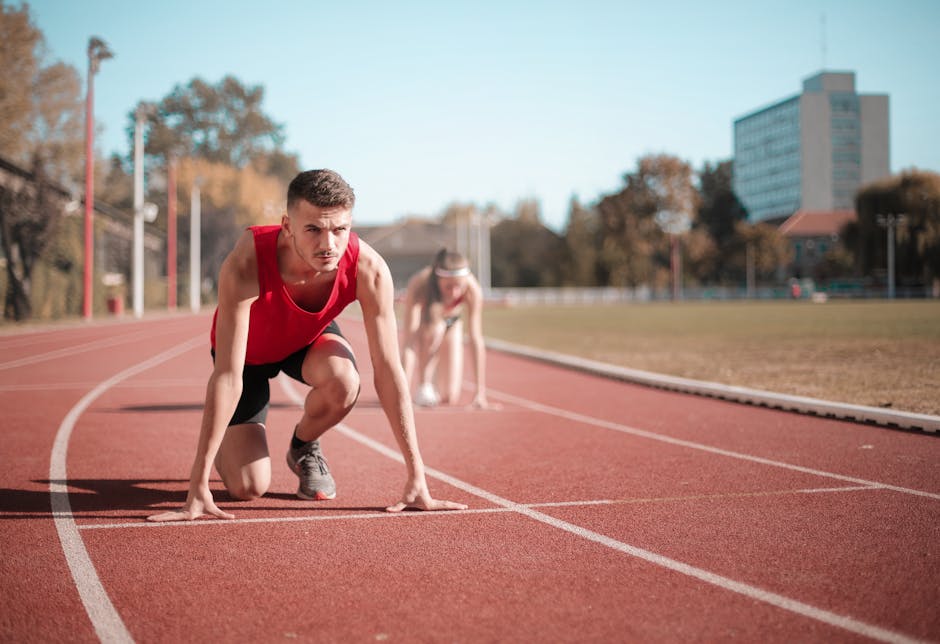 Male athlete in starting position on outdoor track with blurred background