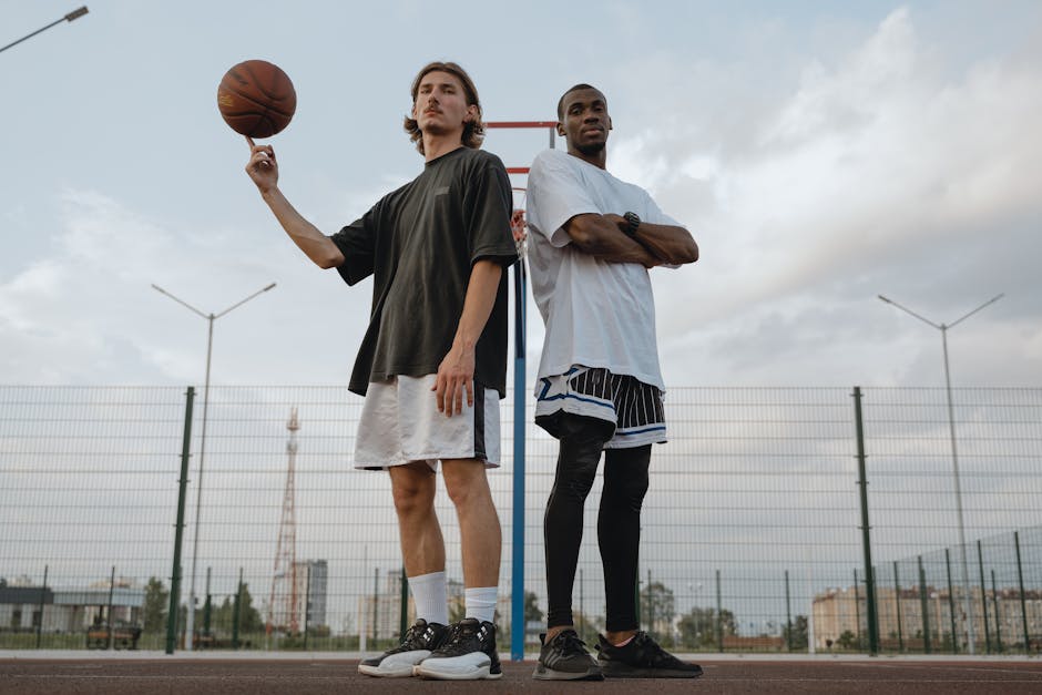 Two men posing with a basketball on an outdoor court, showcasing athletic skill